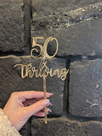 Gold 50th birthday cake topper displayed on a cake